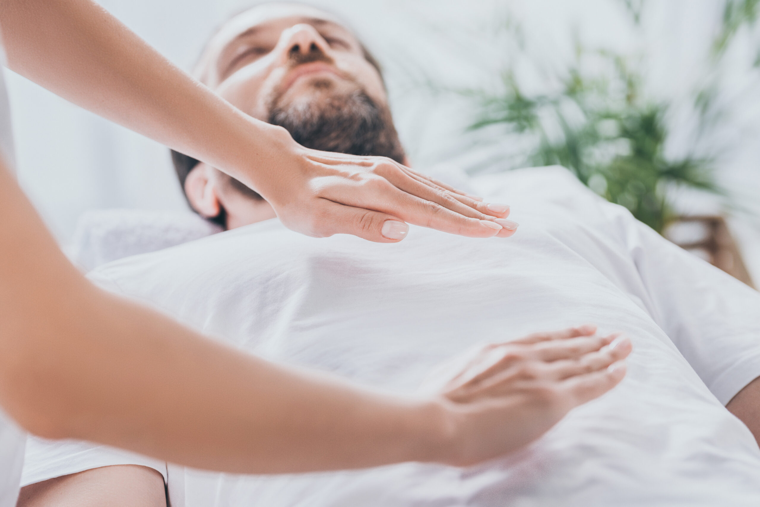 Close-up view of bearded man receiving reiki healing session above stomach and chest